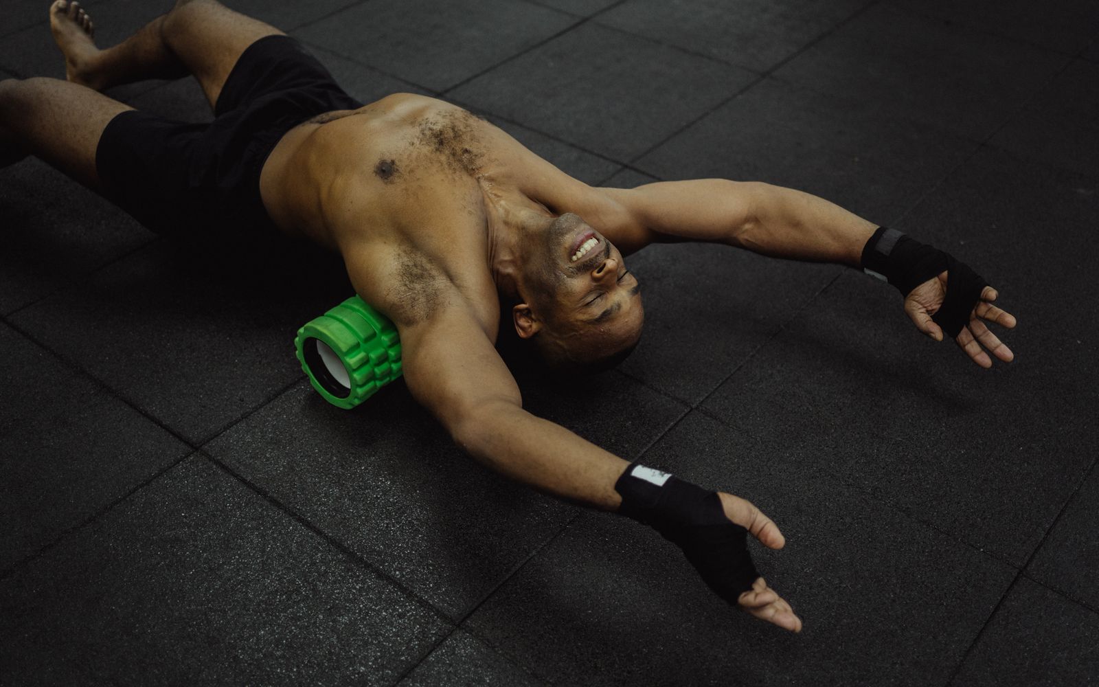 Spor salonunda sırtının üst bölümünü yeşil foam roller ile gevşeten sporcu